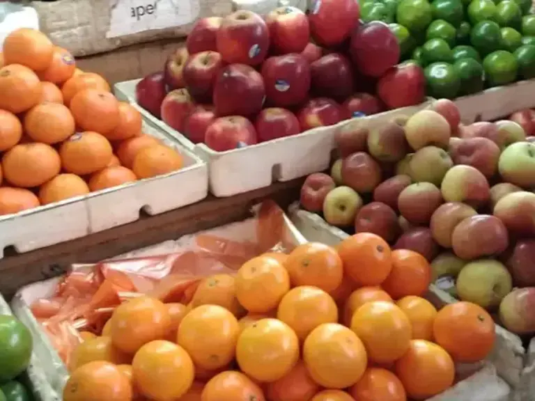 A vendor's colorful arrangement of fresh oranges and apples in the central market fruit section